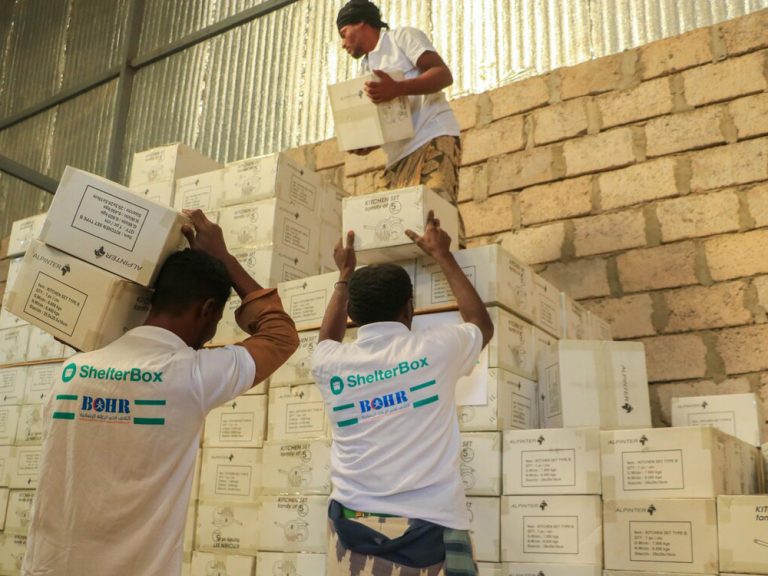 People stacking boxes of aid in a warehouse